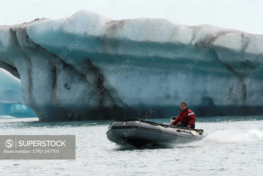Iceland, Austurland Region, man piloting a Zodiac on the Jokulsarlon Glacial Lake in front of an iceberg