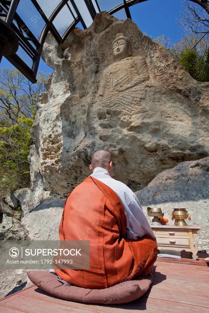 South Korea, North Gyeongsan Province, Gyeongju area, Golgulsa Buddhist temple, monk meditating in front of Buddha statue carved in a rock