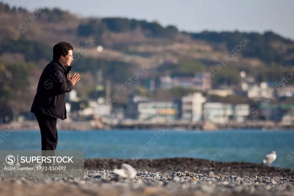 South Korea, North Gyeongsan Province, Gyeongju, Underwater Tomb of King Munmu, Korean woman performing a shamanic prayer on the beach