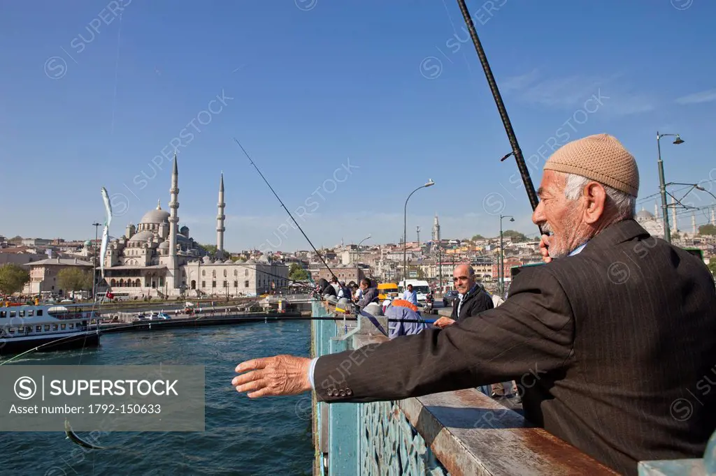 Turkey, Istanbul, fisherman on the Galata bridge spanning the straits of the Golden Horn, in the background the Yeni Cami New Mosque