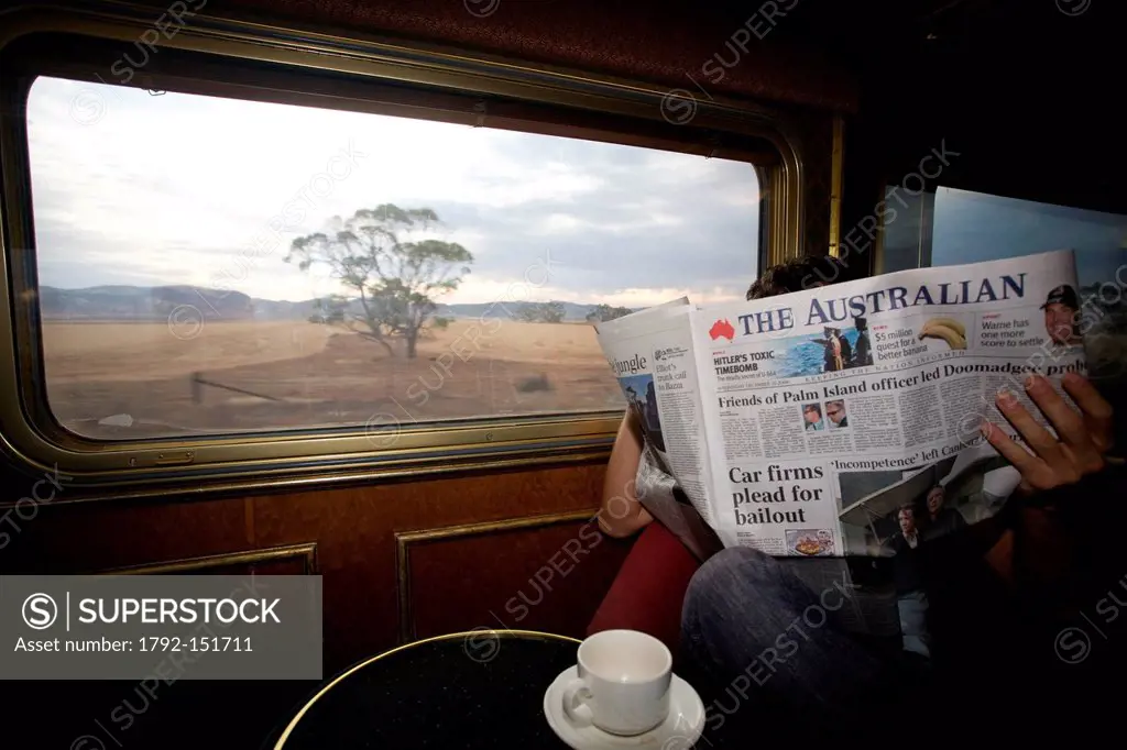 Australia, Northern Territory, Red Center, Alice Springs, a traveller reading a newspaper in the bar coach of The Ghan