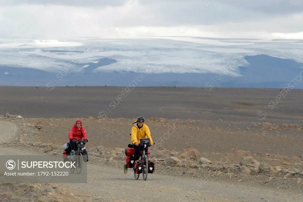 Iceland, Nordurland Vestra Region, two cyclists on the track of Kjolur in a desert landscape with a glacier in the background