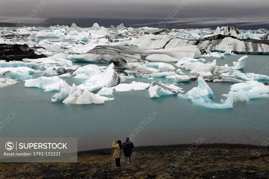 Iceland, Austurland Region, couple in front of the Jokulsarlon Glacial Lake and its icebergs