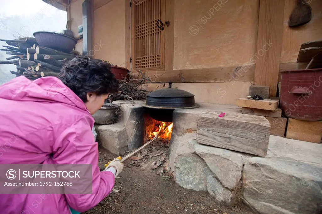 South Korea, North Gyeongsan Province, Pohang, Yangdong Traditional Village, Korean woman lighting the traditional heating system ondol