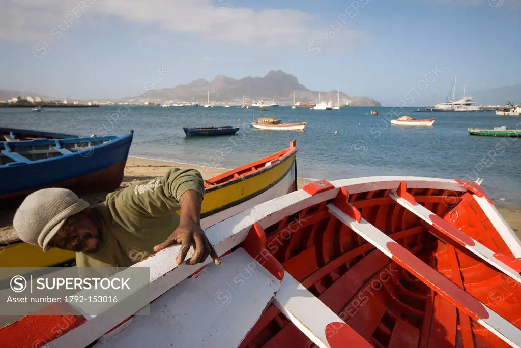 Cape Verde, Sao Vicente island, Mindelo, a fisherman maintains its boat, far off the mountain Montecara