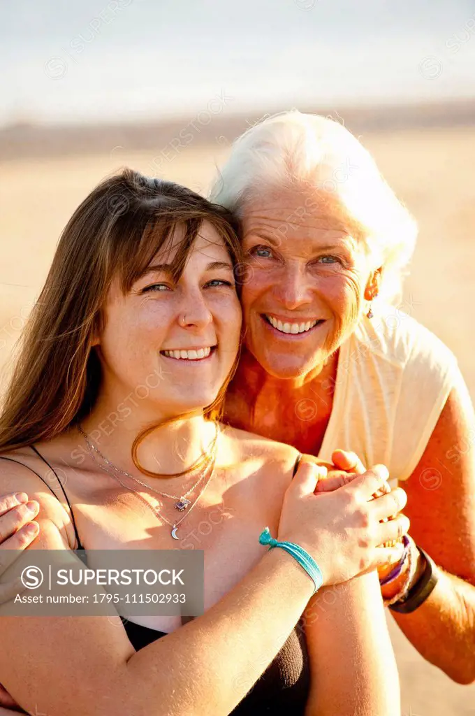 Portrait of mother and adult daughter smiling on beach