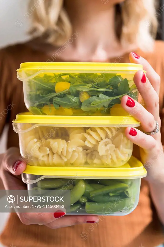 Woman holding stack of food in plastic containers