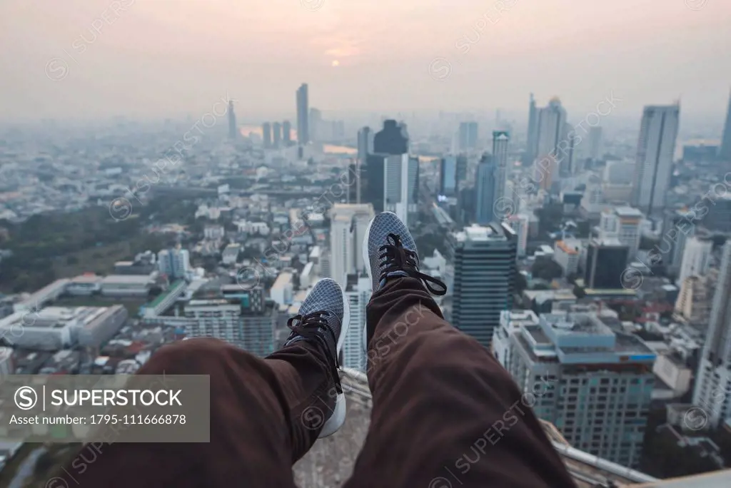 Legs of young man and cityscape of Bangkok, Thailand