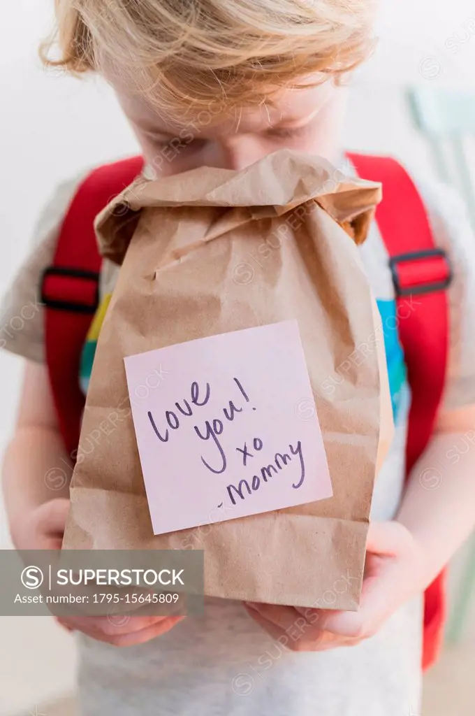Boy (4-5) peeking into lunch bag with note from mom