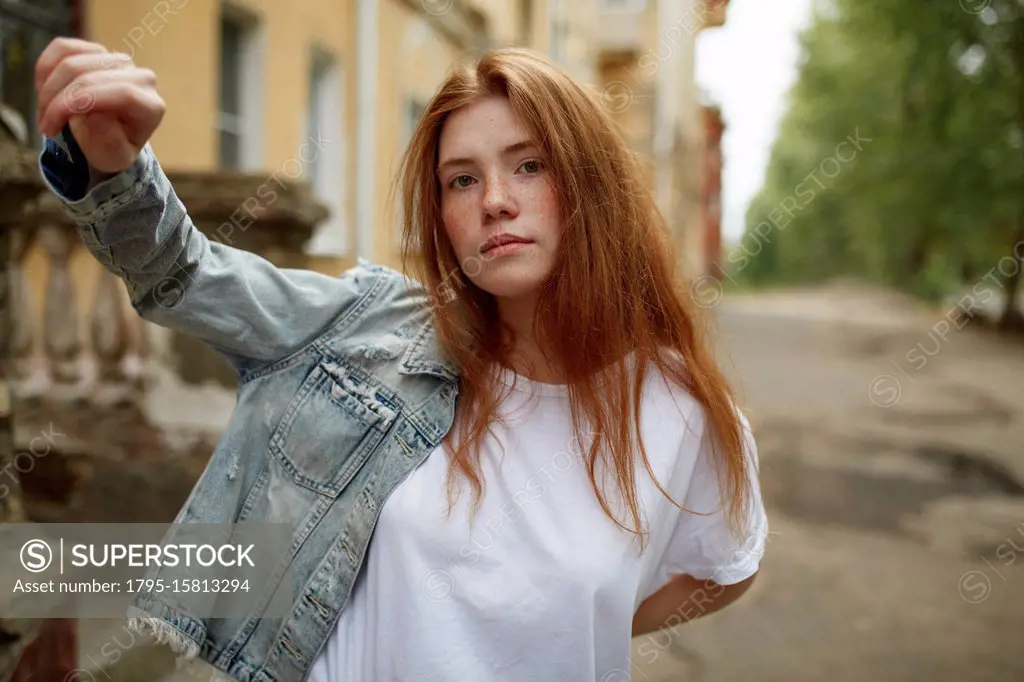 Teenage girl putting on denim jacket