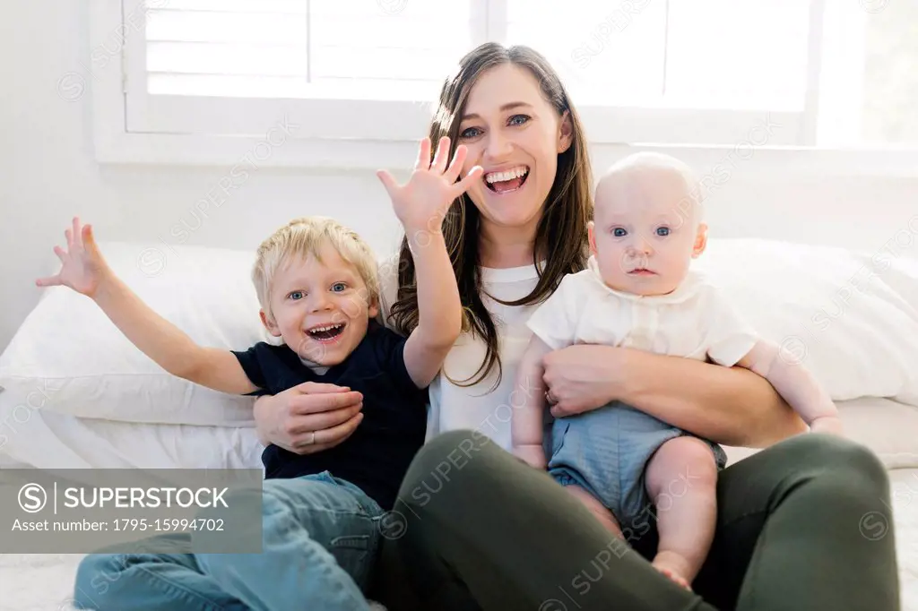 Smiling woman and her sons on bed