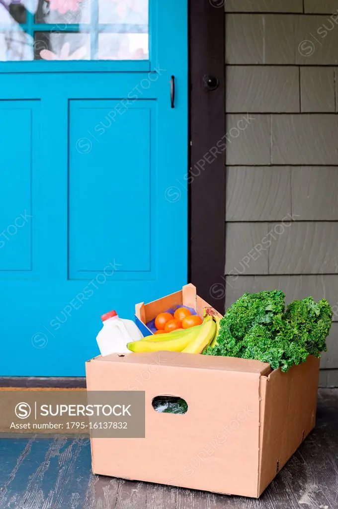 Box of delivered produce on house porch