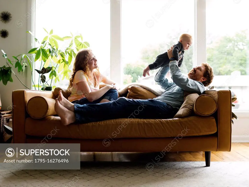 Mother and father playing with baby son (6-11 months) on sofa