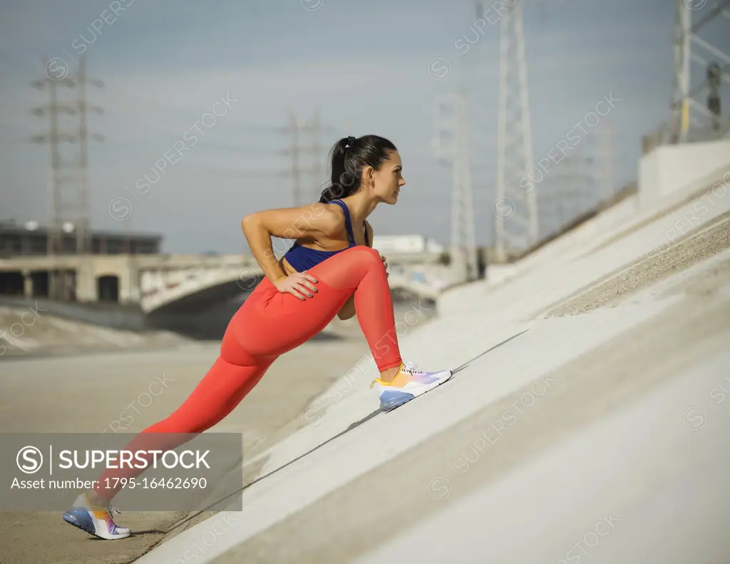 USA, California, Los Angeles, Sporty woman stretching in urban setting