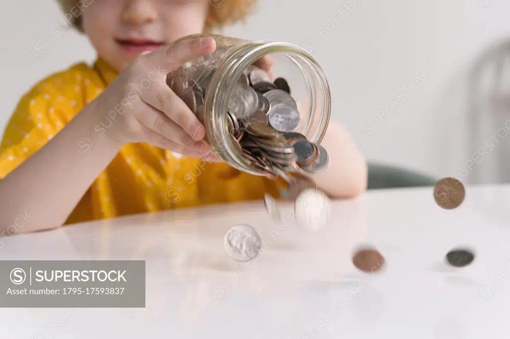 Boy (4-5) removing coins from jar
