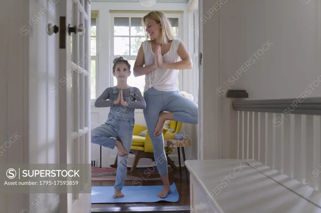 Mother with daughter (6-7) practicing yoga together at home