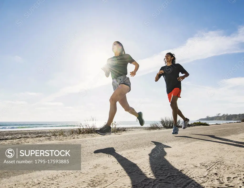 USA, California, Dana Point, Man and woman running together by coastline