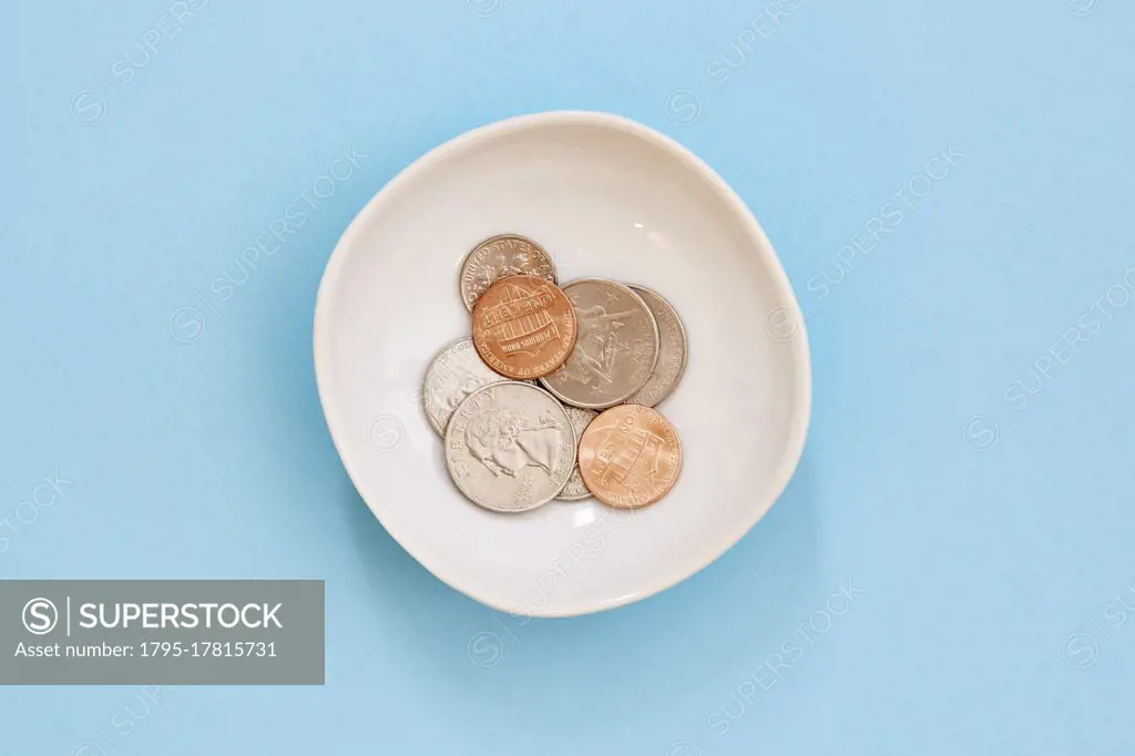 Coins in bowl on blue background