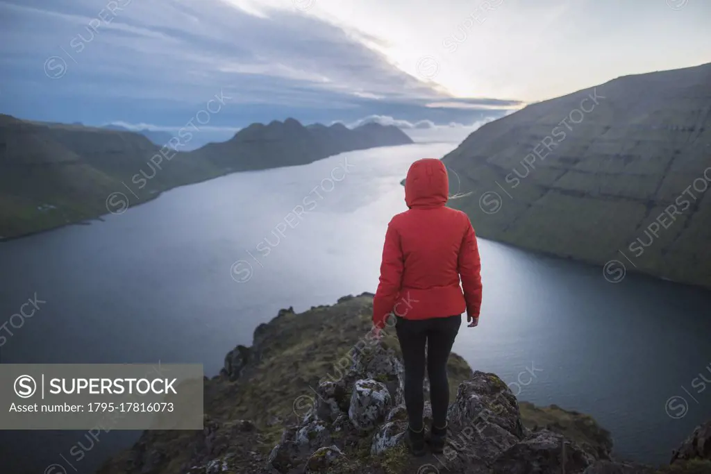 Denmark, Faroe Islands, Klaksvik, Woman standing on top of Klakkur mountain over sea and looking at view