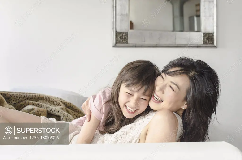 Mother and daughter laughing on sofa