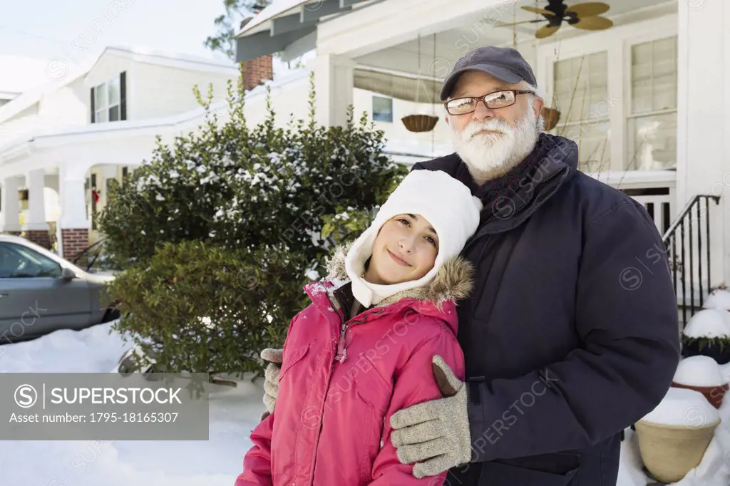 Grandfather and granddaughter outside house in winter