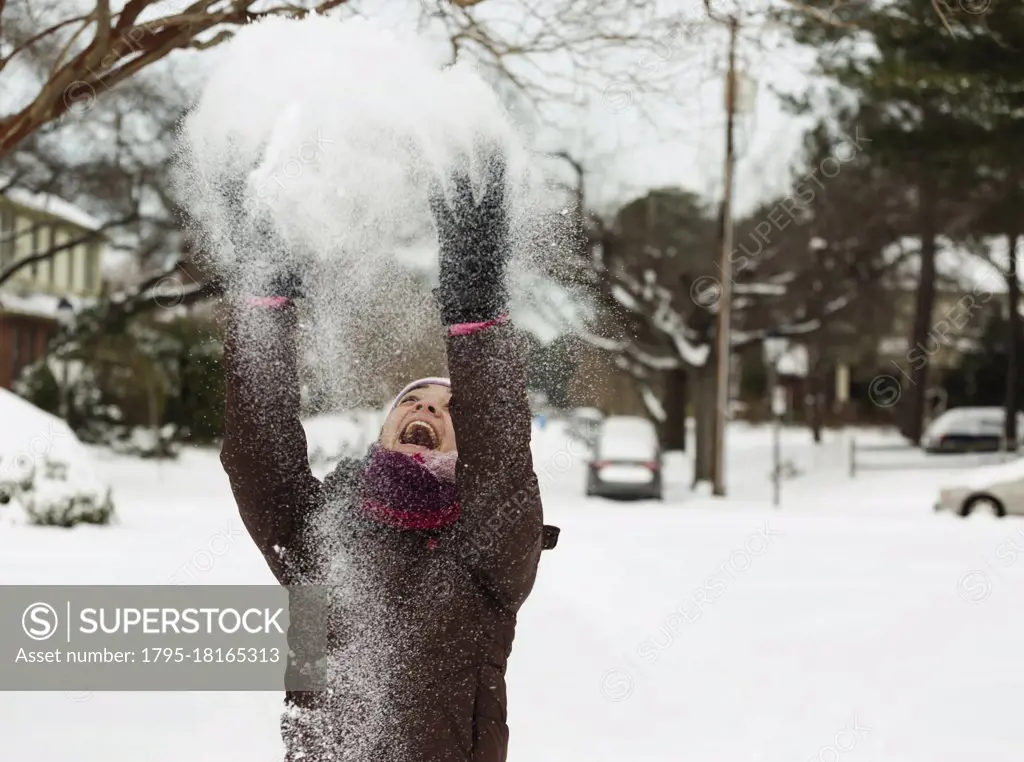 Teenage girl throwing powdered snow mid air