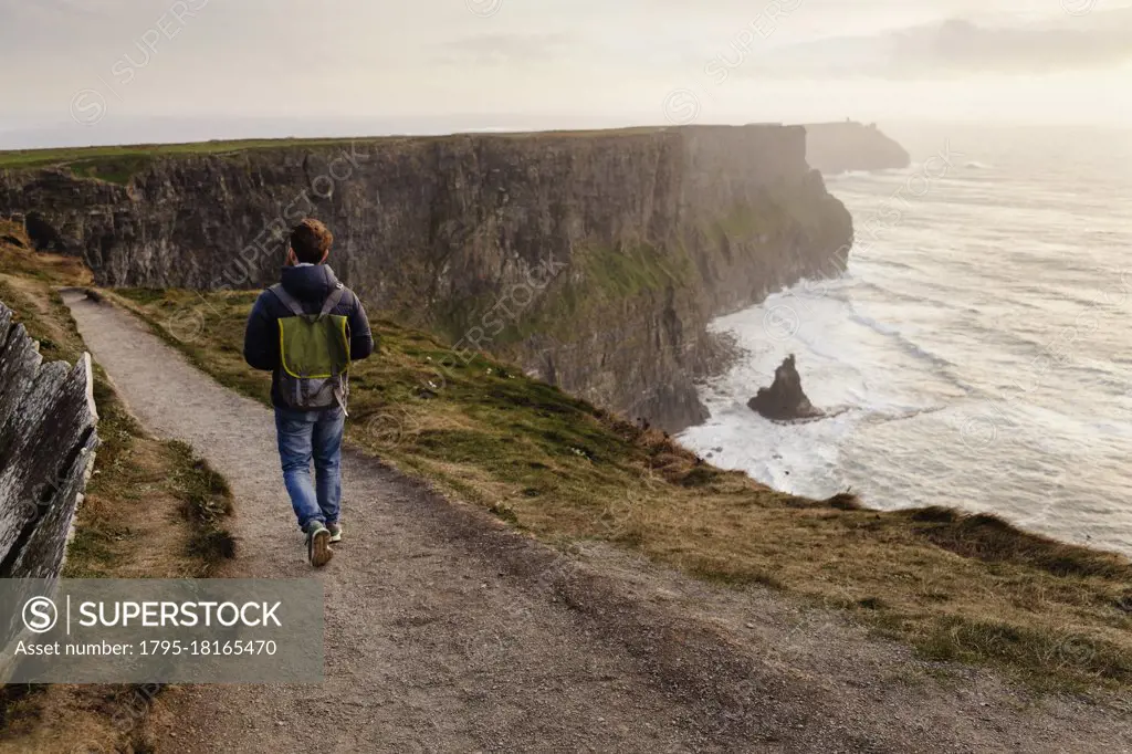 Mid adult man walking on The Cliffs of Moher, The Burren, County Clare, Ireland