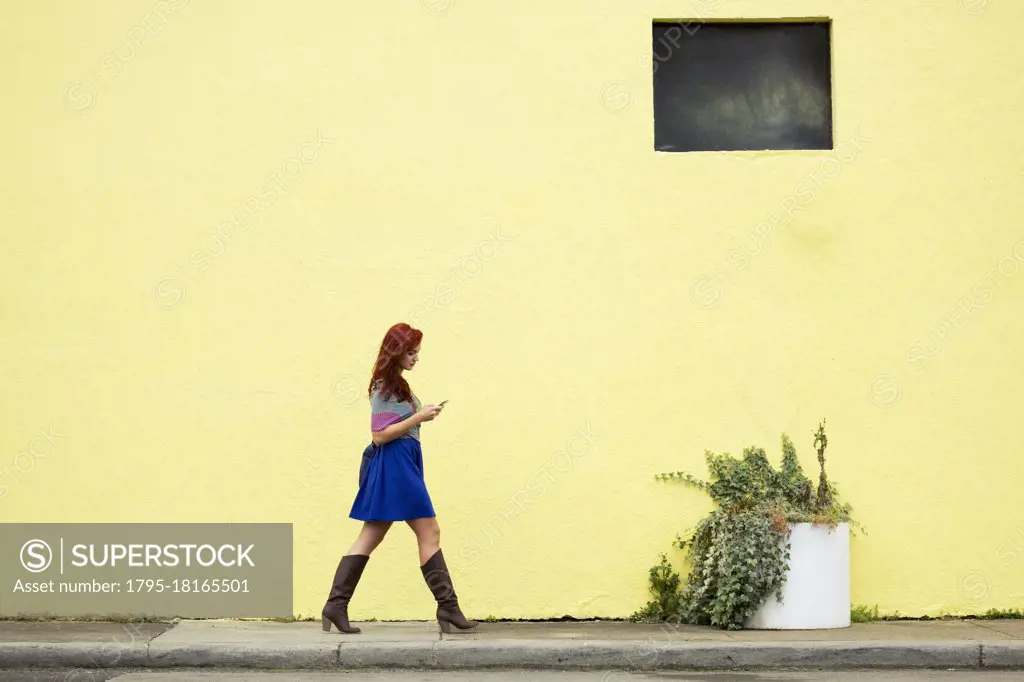 Young woman with red hair, walking along street