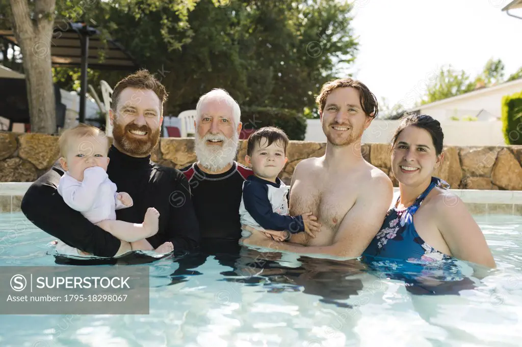 Portrait of family with boys (12-17 months, 2-3) in swimming pool