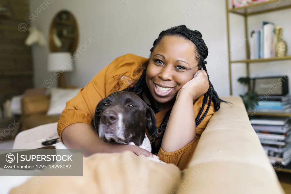 Smiling woman hugging dog on sofa