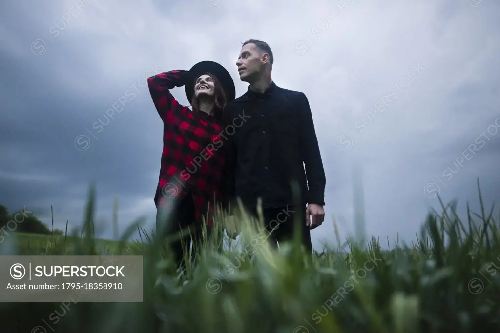 Young couple wrapped in wheat field on overcast day