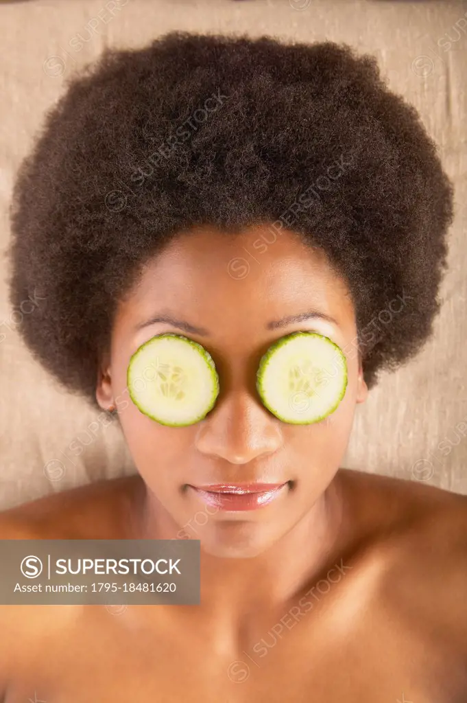 Woman with cucumber slices over eyes