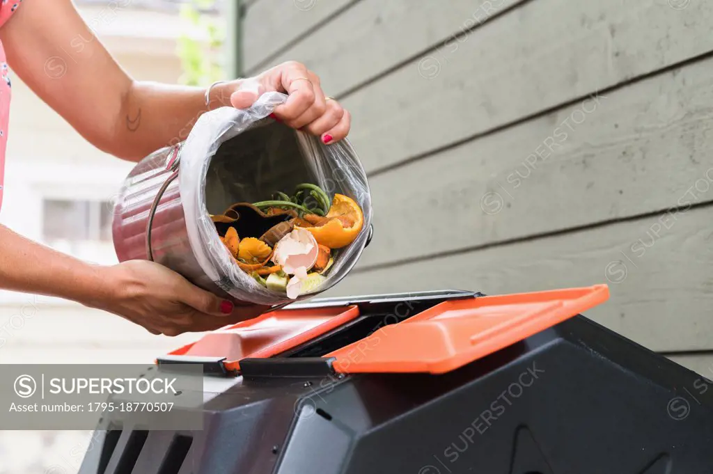 Close-up of woman putting kitchen scraps into compost bin
