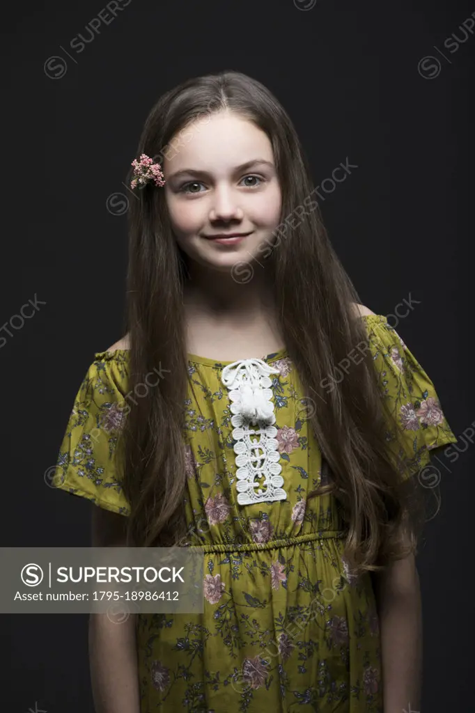 Studio portrait of smiling girl (10-11) in green dress with flower in hair