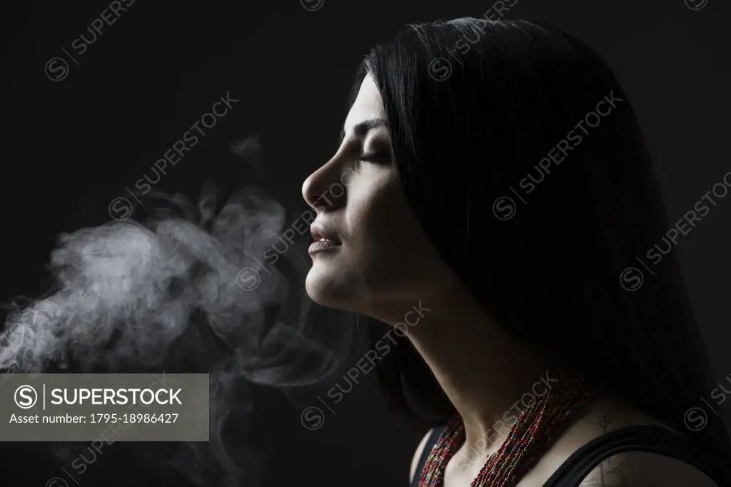 Profile of woman with smoke against black background