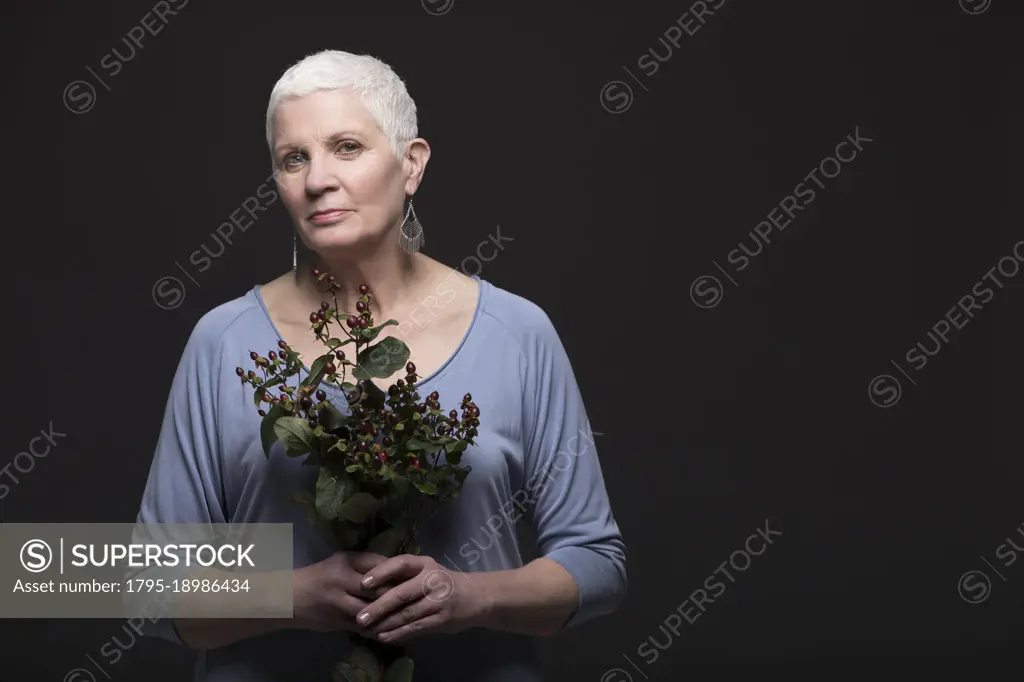 Studio portrait of woman in blue shirt holding bunch of flowers
