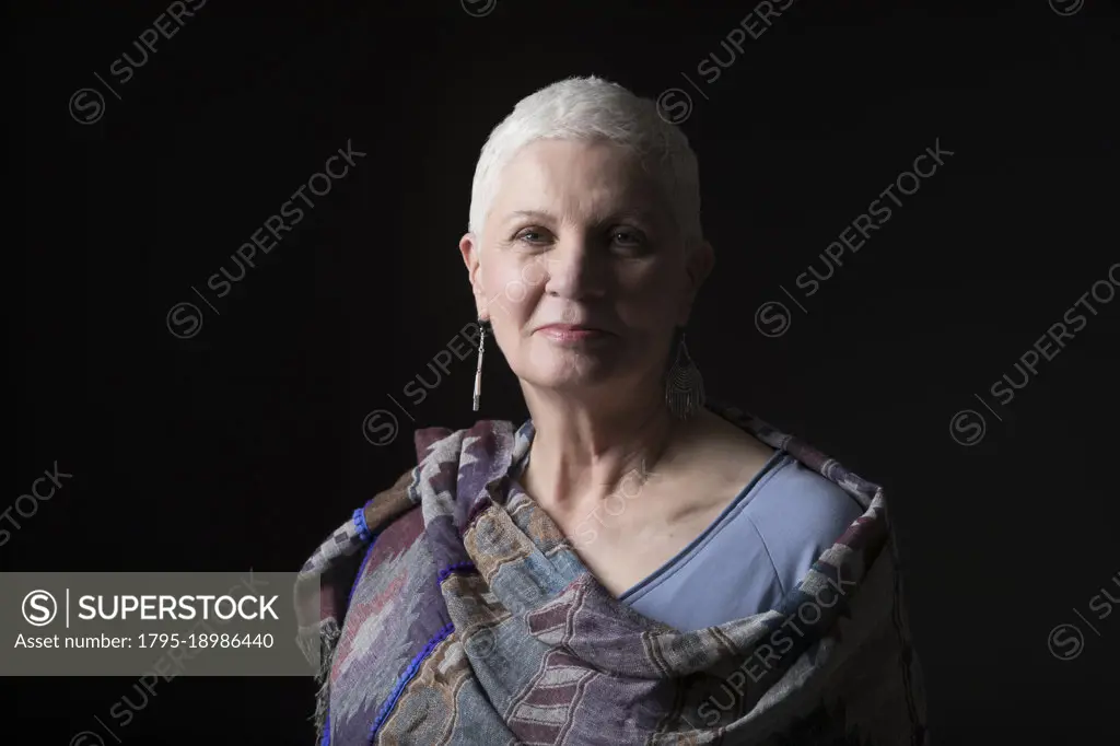 Studio portrait of woman with white short hair wrapped in shawl