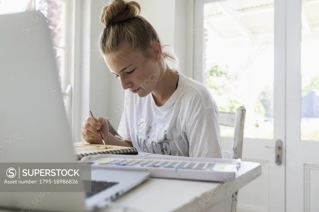 Girl (16-17) working on watercolor drawing in studio