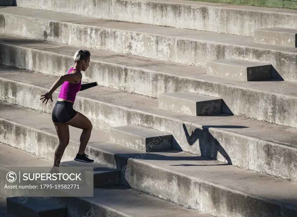 Woman with amputated hand jogging up steps