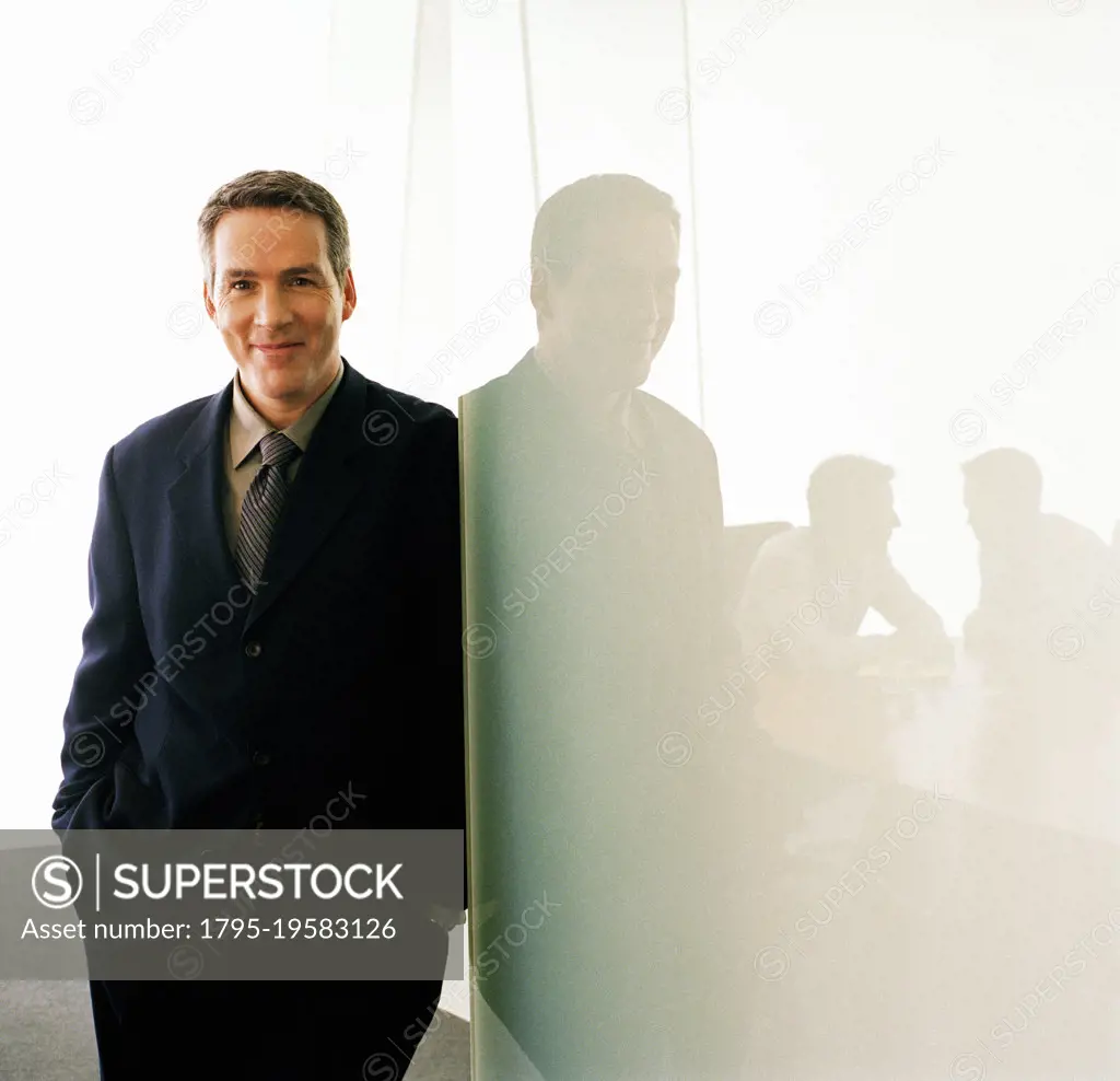 Portrait of business executive leaning against glass wall