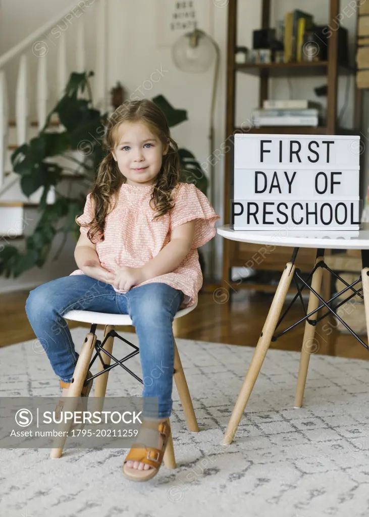 Portrait of girl (2-3) sitting at First Day of Preschool sign