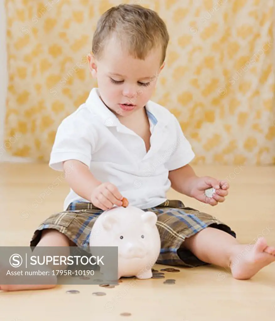 Baby putting coins in piggy bank