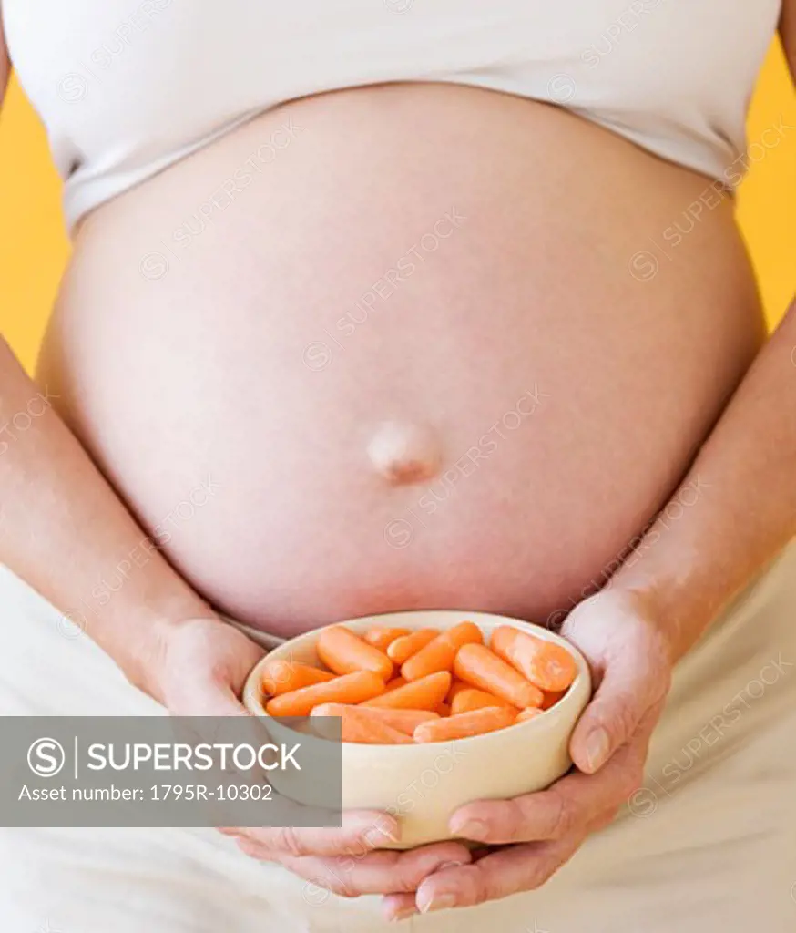 Pregnant woman holding bowl of carrots