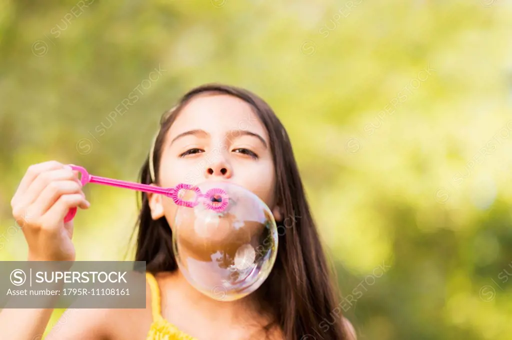 Portrait of girl (8-9) blowing bubbles