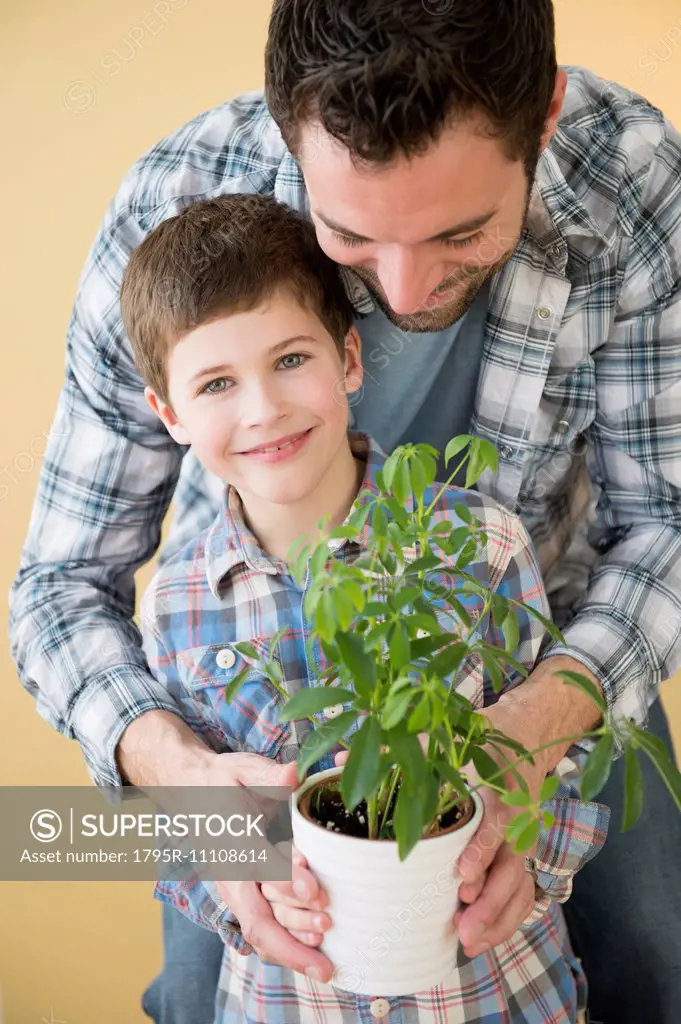Father and son (8-9) holding potted plant