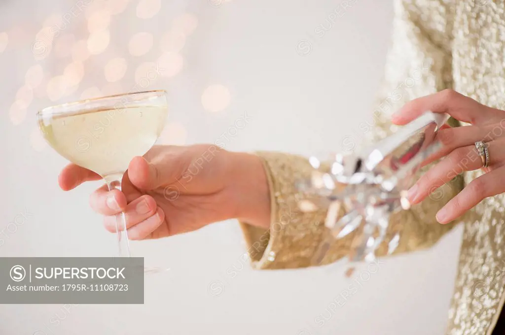 Studio Shot of female's hands holding champagne and noisemaker