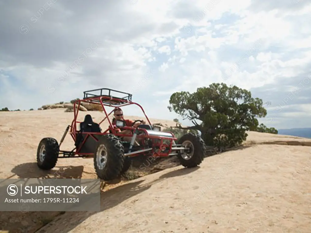 Man in off-road vehicle on rock formation