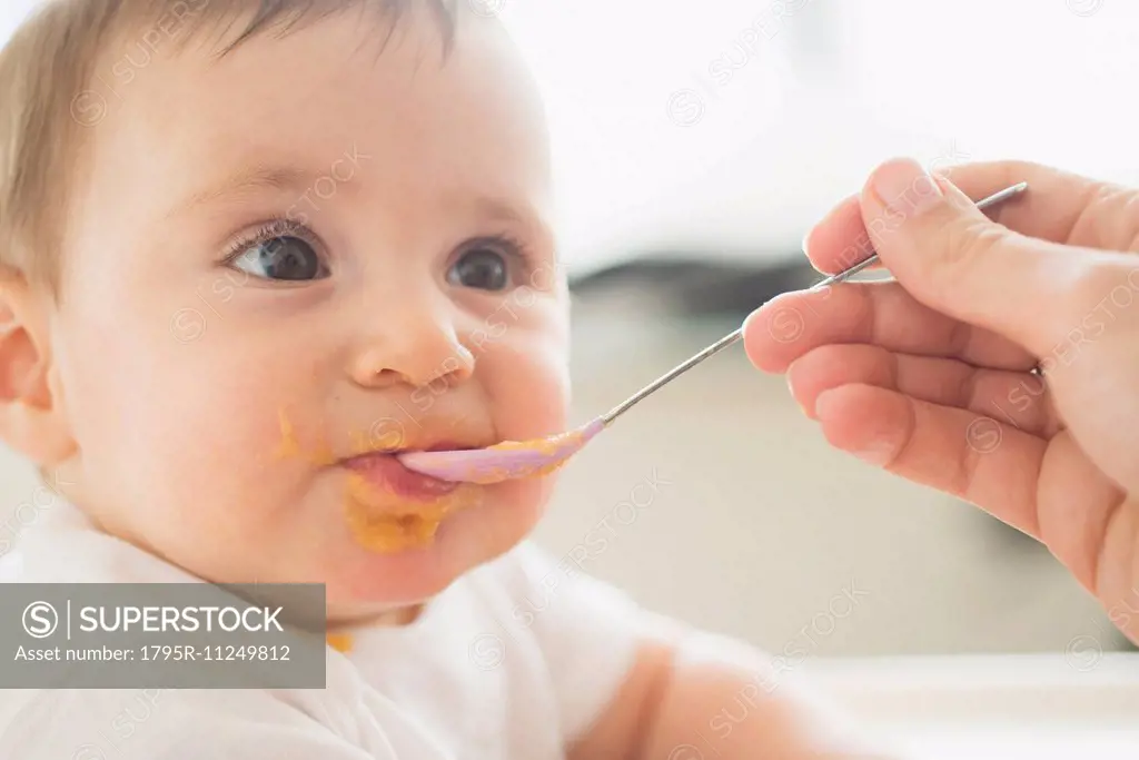 Close-up of baby girl (12-17 months) being spoon fed
