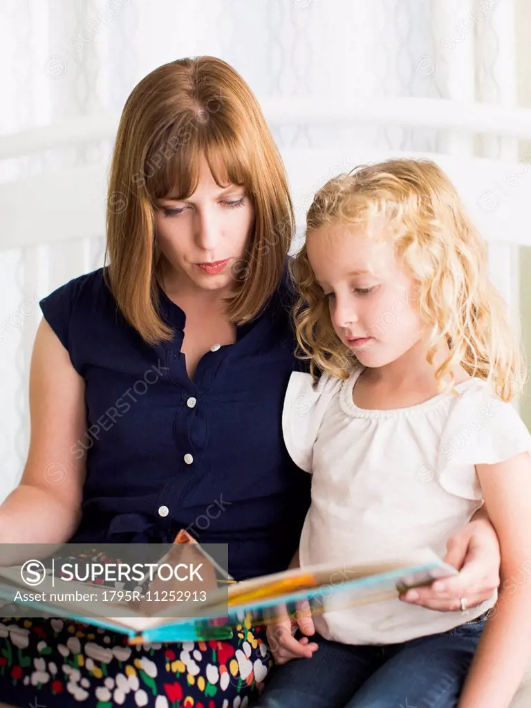 Mother reading book with daughter (6-7)
