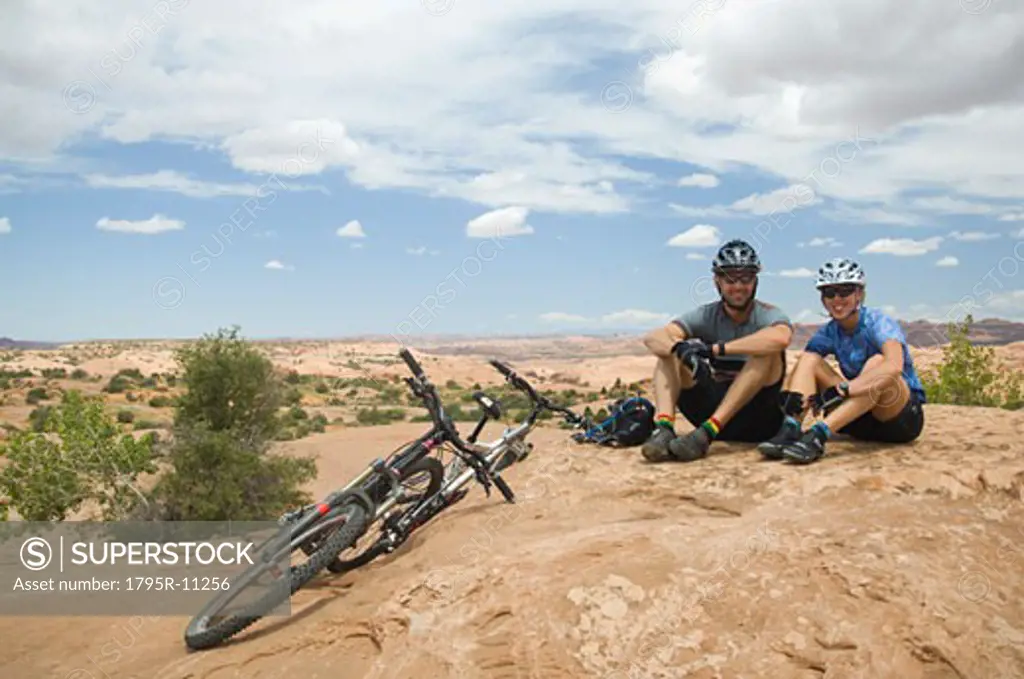 Cyclists sitting next to mountain bikes in desert